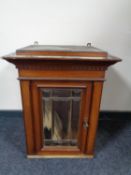 An antique continental mahogany wall cabinet with bevelled glass panel door