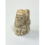 A carved Chinese bone netsuke - village elder with staff