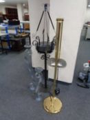 A wrought iron plant stand together with two metal candle holders and brass floor standing lamp