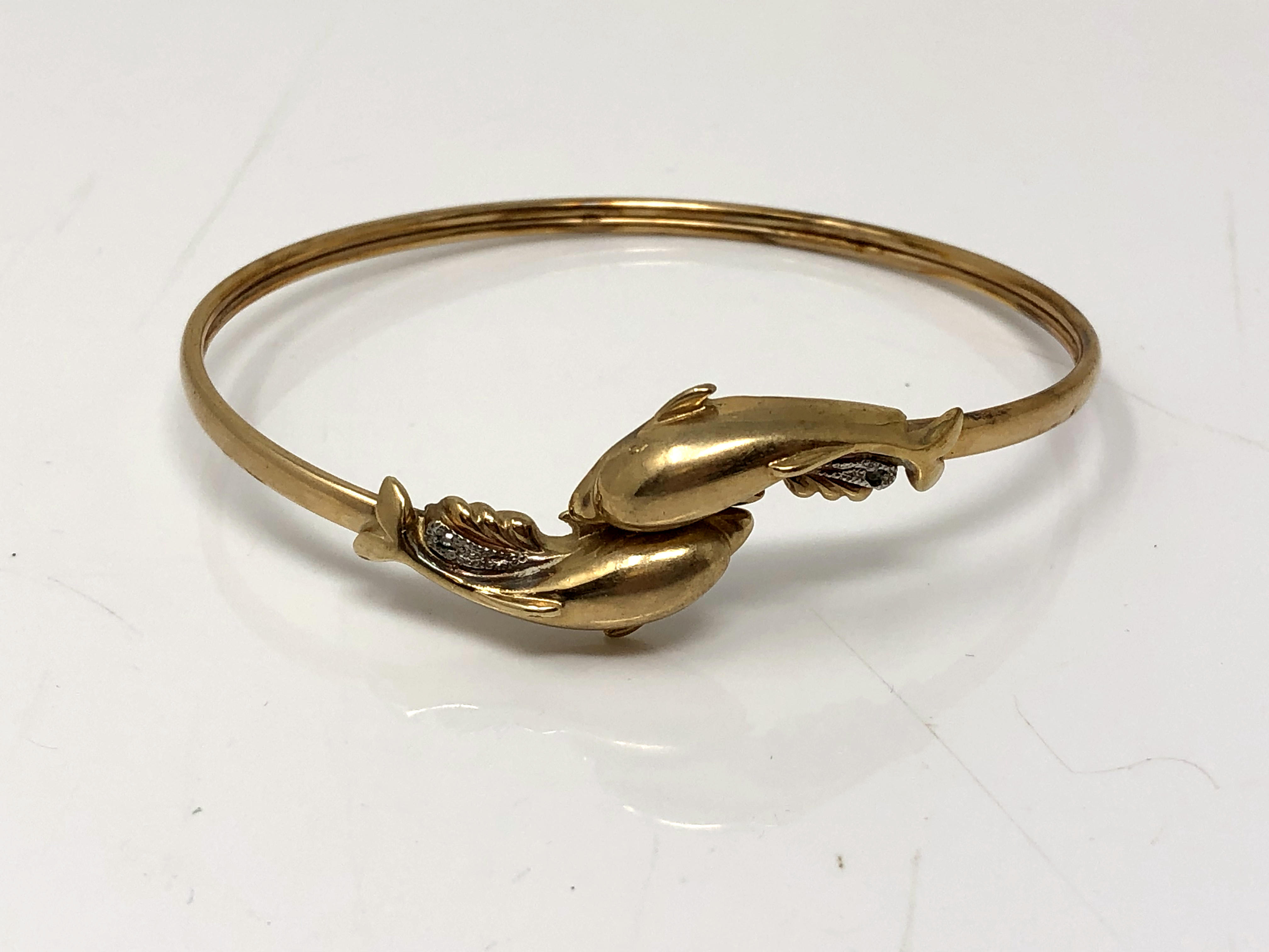 A 9ct gold dolphin bangle set with diamonds CONDITION REPORT: 7.