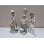 Three Nao figures of a girl with a puppy, girl with chicken and girl with wash tub.