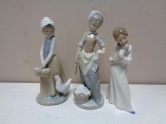 Three Nao figures of a girl with a puppy, girl with chicken and girl with wash tub.