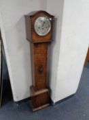 An oak cased granddaughter clock with silvered dial