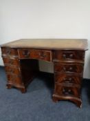 A mahogany twin pedestal nine drawer writing desk with brown tooled leather inset panel