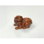 A carved Chinese hardwood netsuke - Lion seated