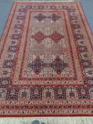 A machine made Eastern design carpet on red ground,