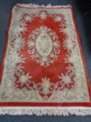 A fringed Chinese rug on red ground