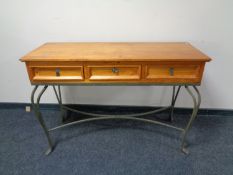 A contemporary pine three drawer console table on wrought metal base