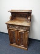 A late Victorian heavily carved oak double door cabinet fitted a drawer with green man decoration