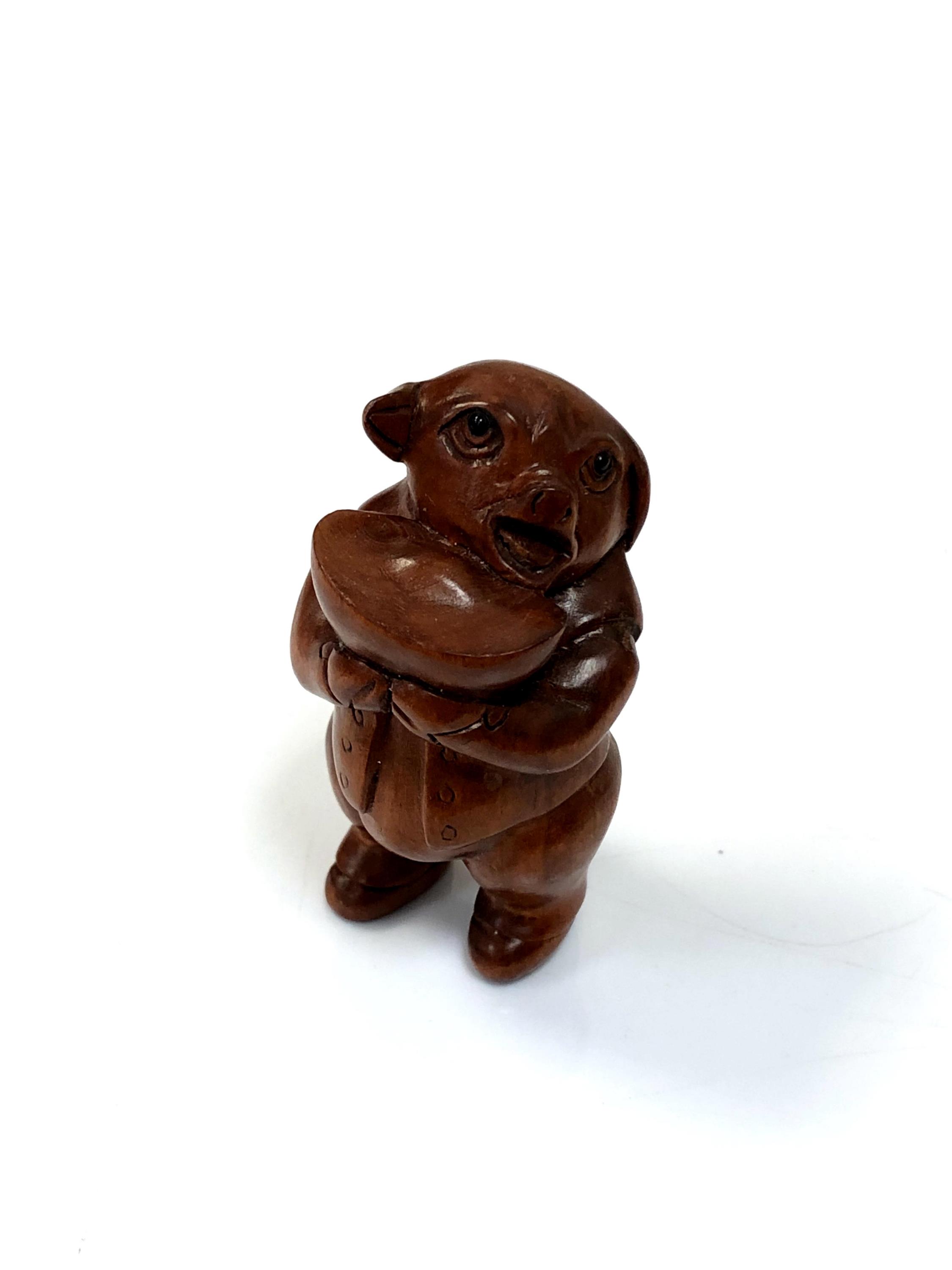 A carved Chinese hardwood netsuke - Pig holding a bowl