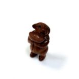 A carved Chinese hardwood netsuke - Pig holding a bowl