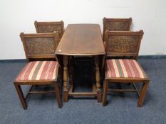 An oak gate leg table and set of four oak dining chairs with carved panel backs in striped