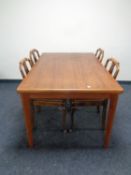 A teak dining table together with a set of four beech dining chairs with faux leather seats