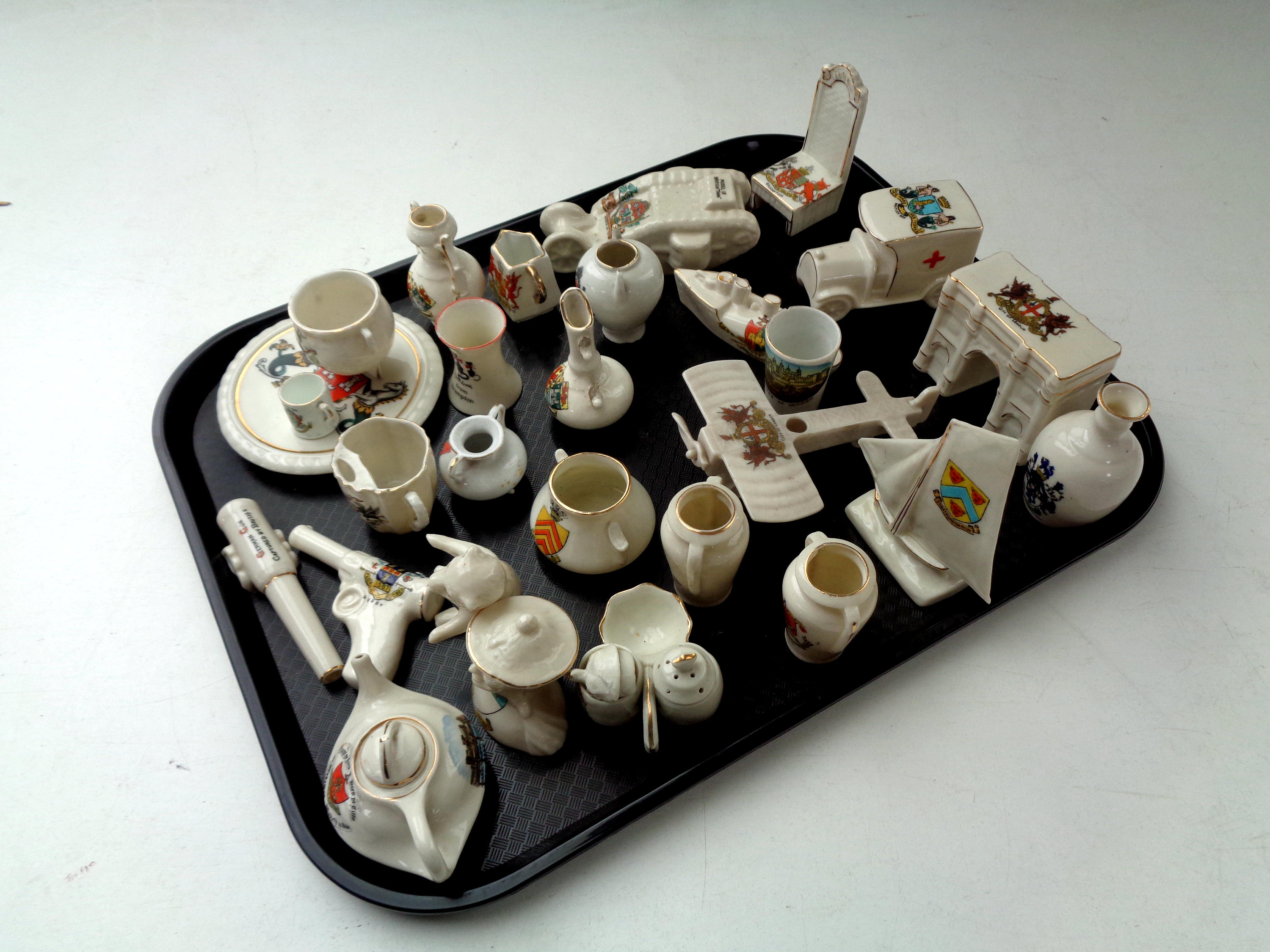 A tray containing English crested china including World War I tank, aircraft,