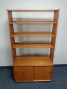 A set of teak open bookshelves fitted sliding door cupboard beneath