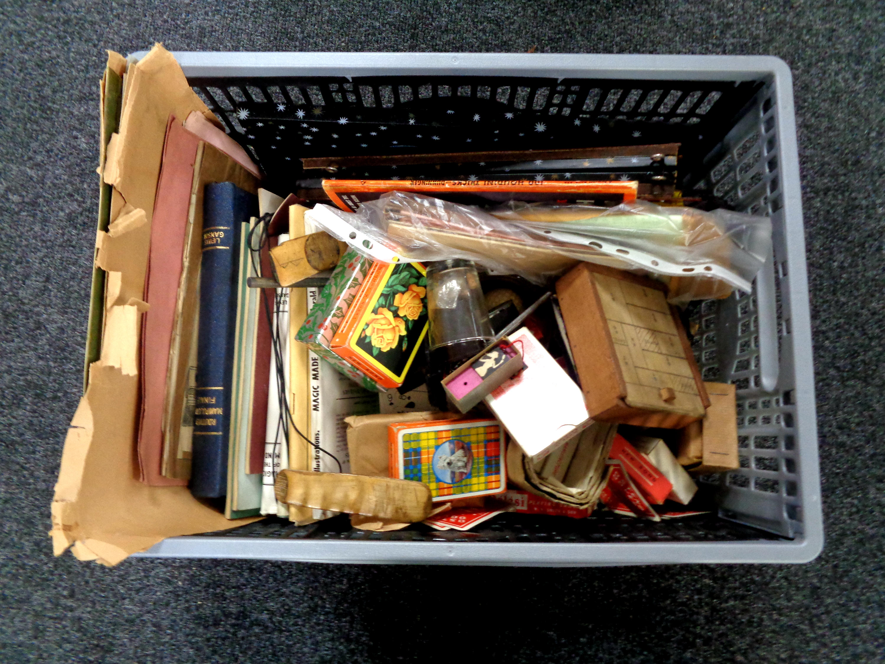 A crate containing a collection of playing cards, books relating to magic,