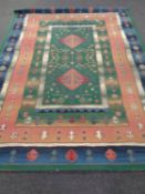 A machine made eastern design carpet on green ground 320 x 240 cm