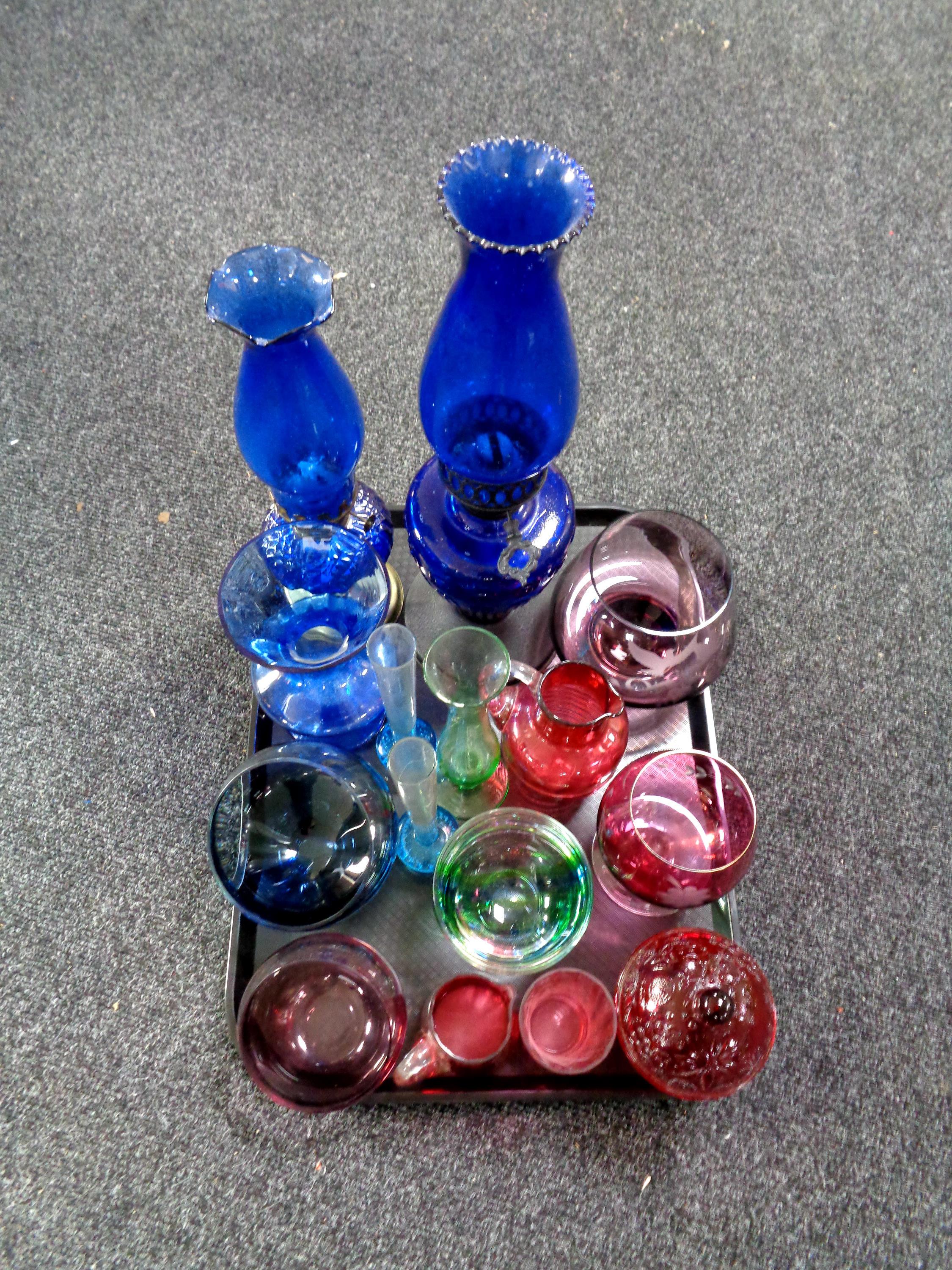 A tray containing two blue glass oil lamps, etched and coloured glassware including lidded bowl,