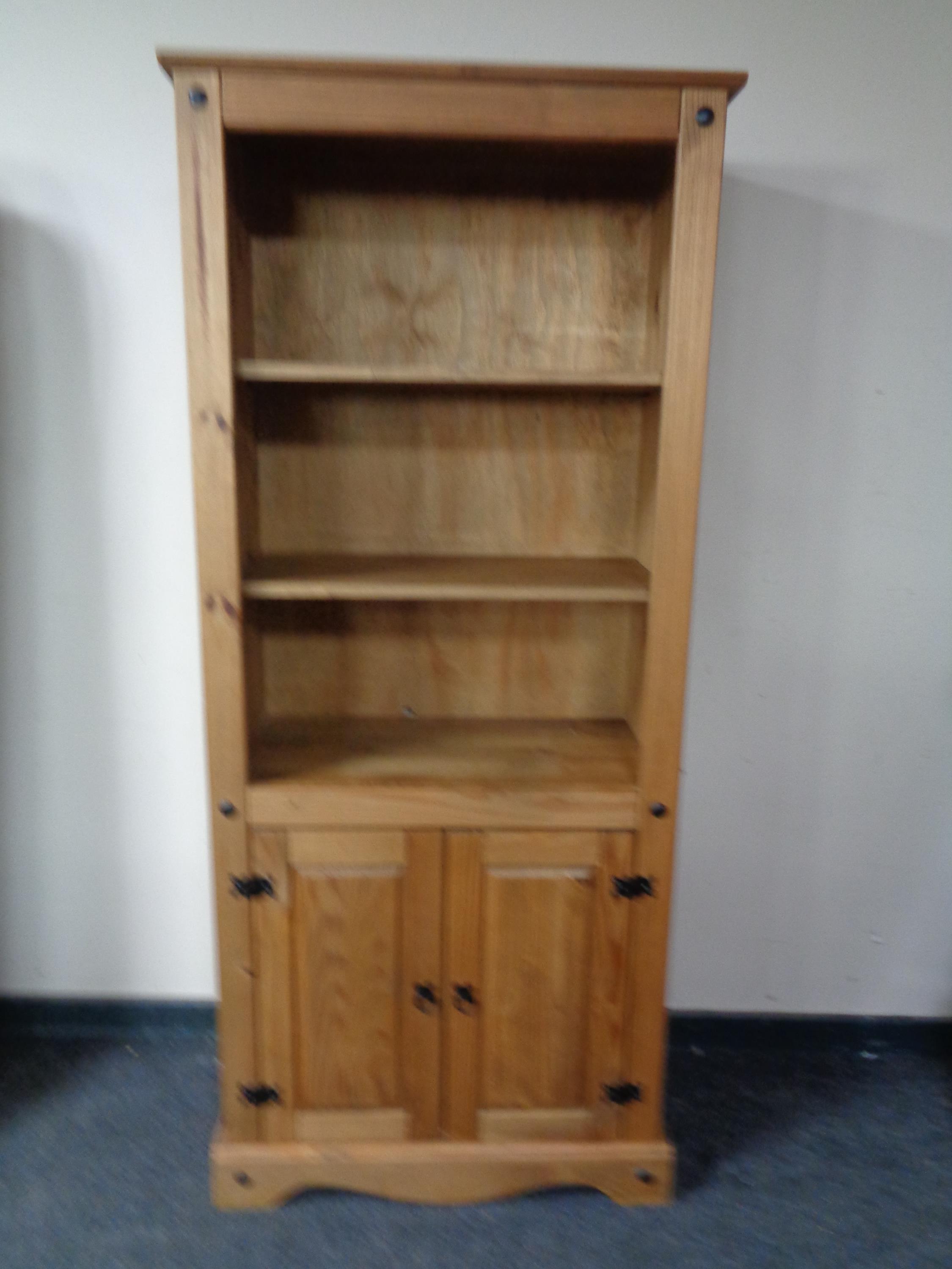 A pine bookcase fitted cupboard beneath
