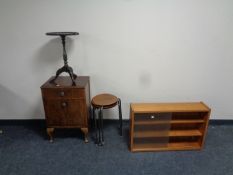 A small teak sliding glass door bookshelf together with a set of three wood and metal stools,