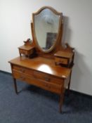 A late Victorian inlaid mahogany three drawer dressing table on raised legs with shield mirror