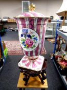 A contemporary ceramic floral pattern lidded vase on a wooden stand