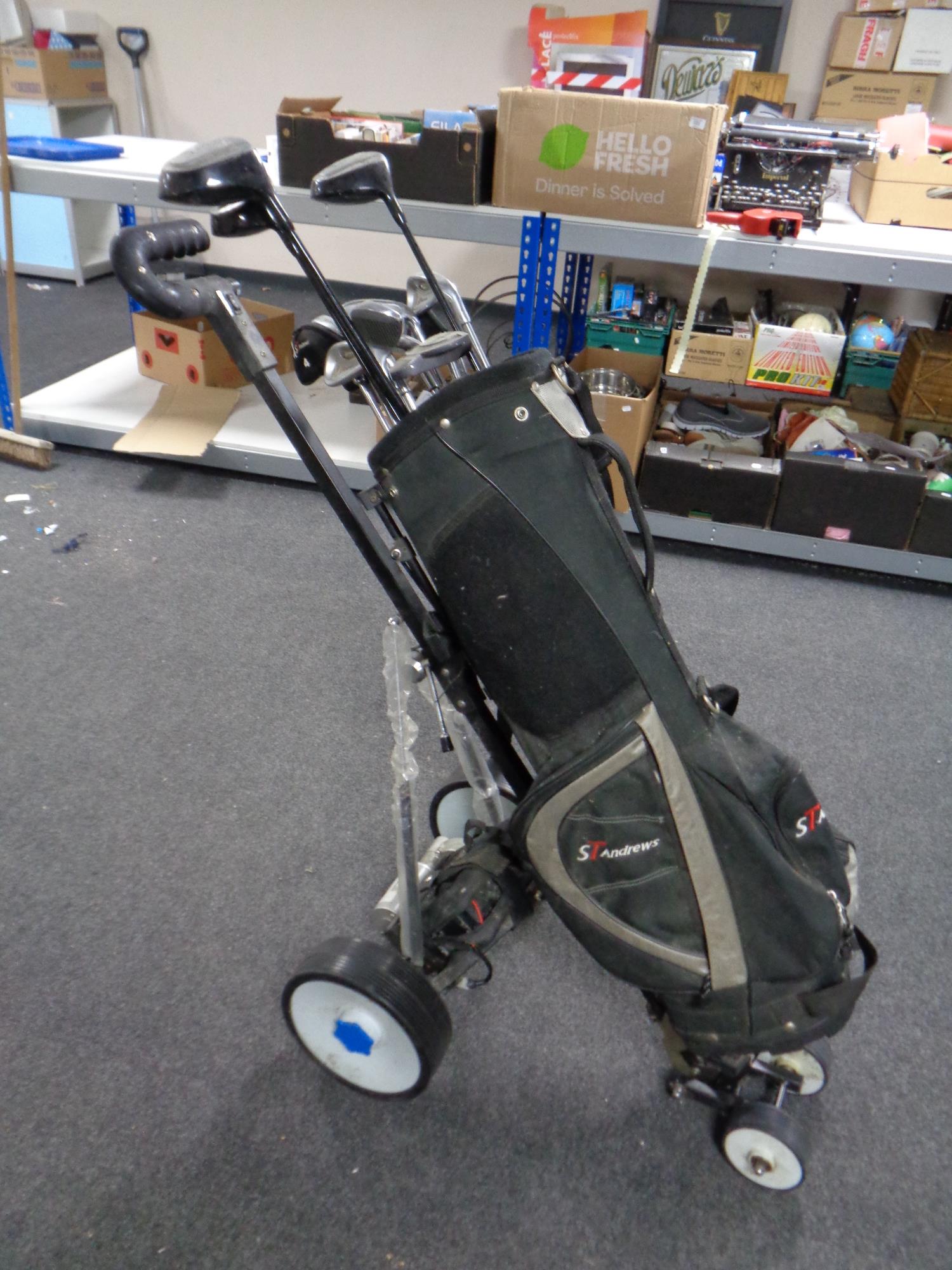 An electric golf cart together with a St Andrews golf bag containing irons and drivers