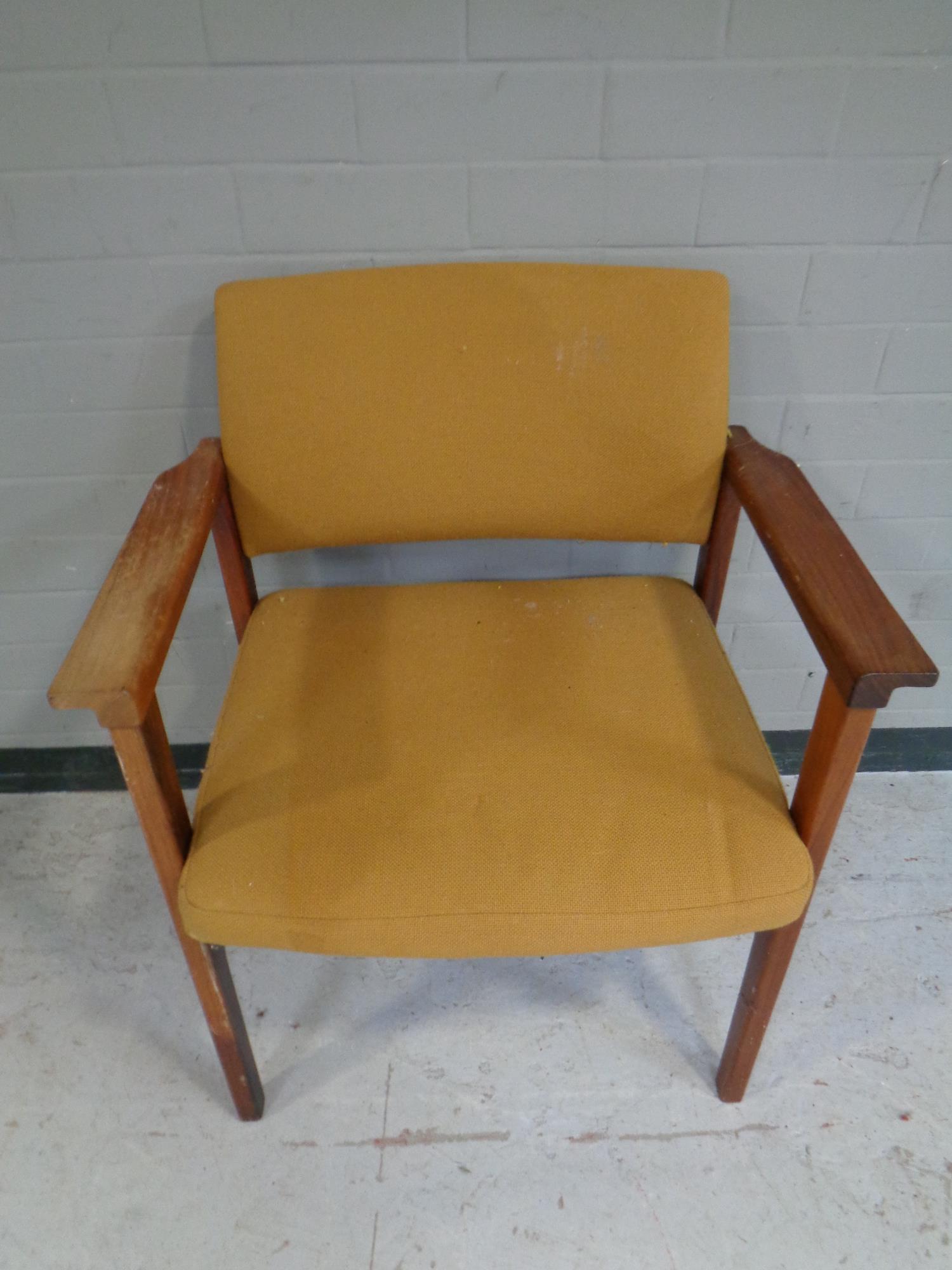 A mid 20th century teak armchair upholstered in an orange fabric