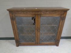 A carved oak double leaded glass door bookcase