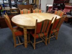 A circular blonde oak extending dining table with two leaves together with a set of six chairs