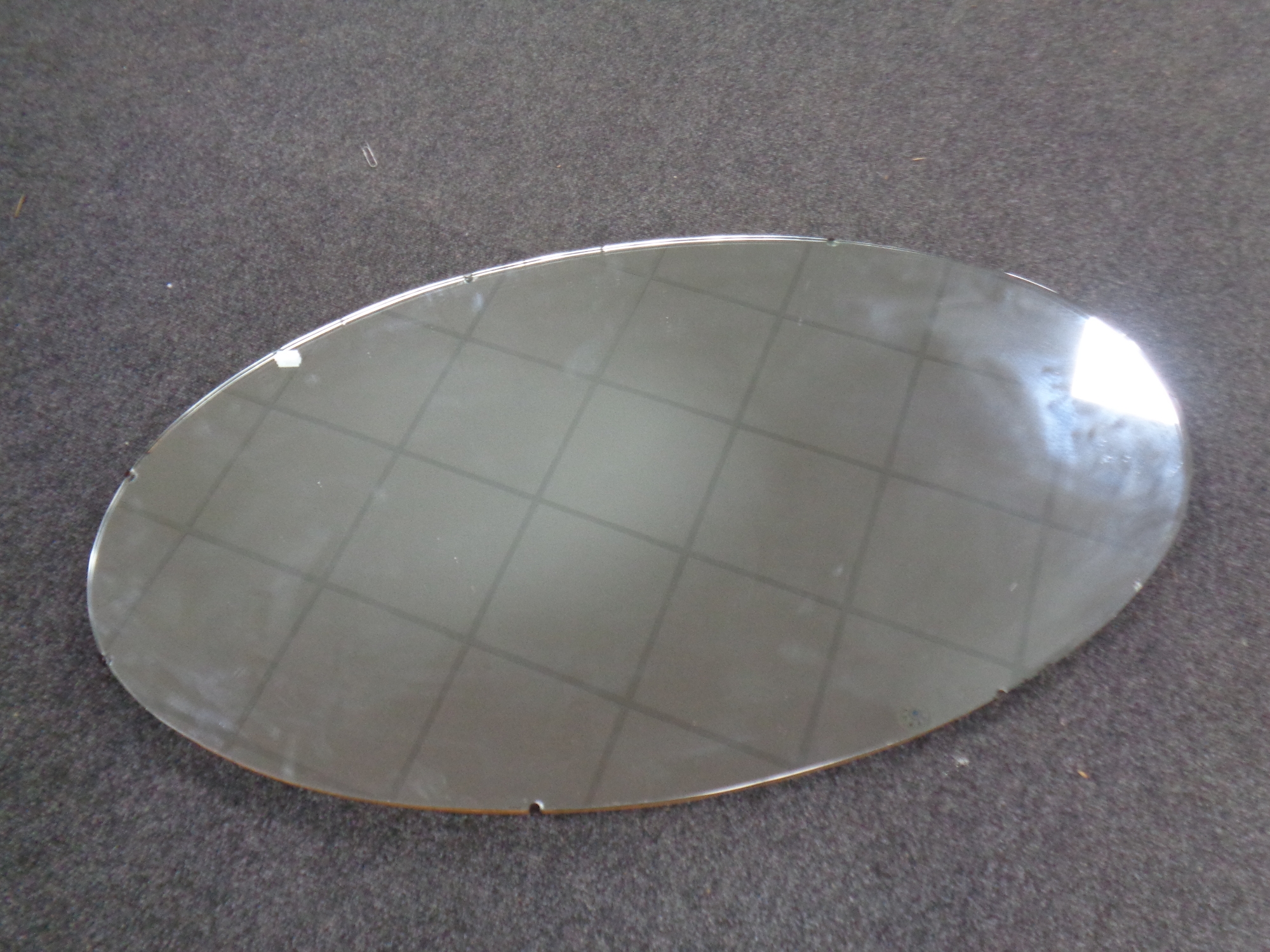 A large oval frameless mirror