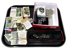 A tray containing costume jewellery and cigarette cards.