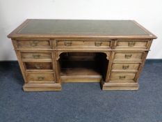 A 19th century oak twin pedestal desk fitted nine drawers with a green tooled leather inset panel
