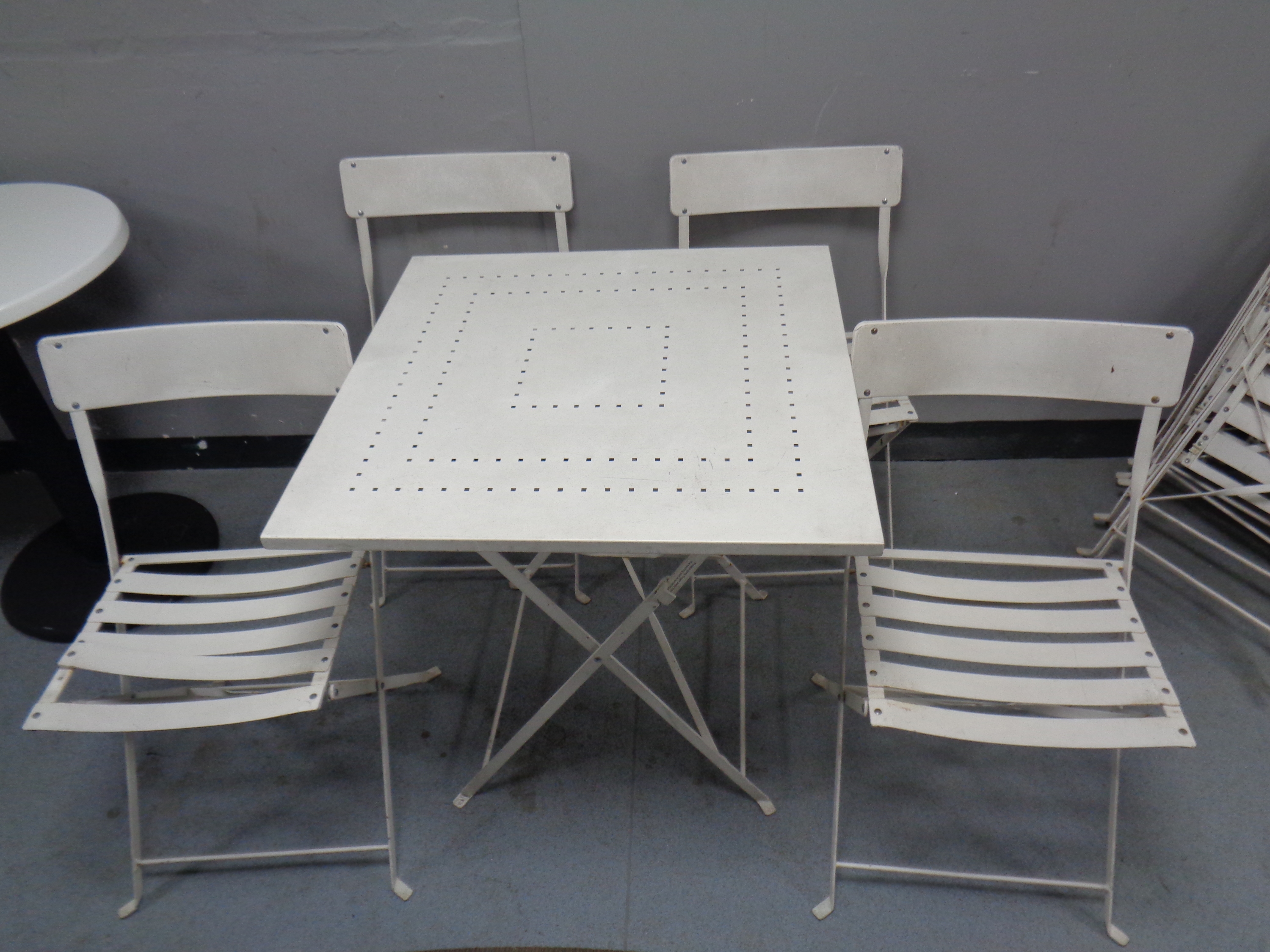 A folding metal square cafe table and four chairs