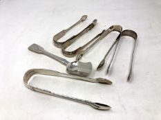 Five pairs of Georgian/William IV sugar tongs and a spoon,