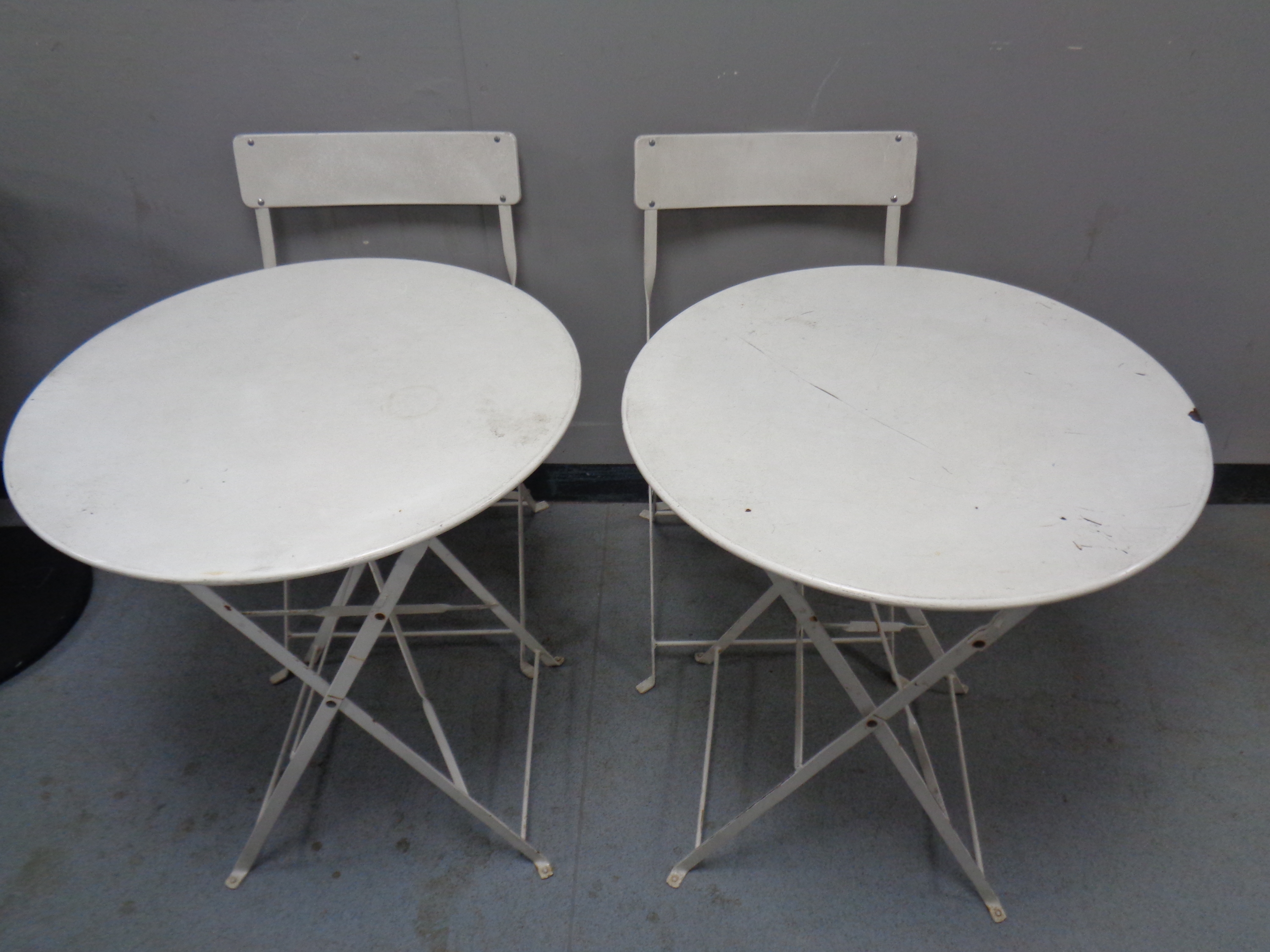 Two circular metal cafe tables and two chairs