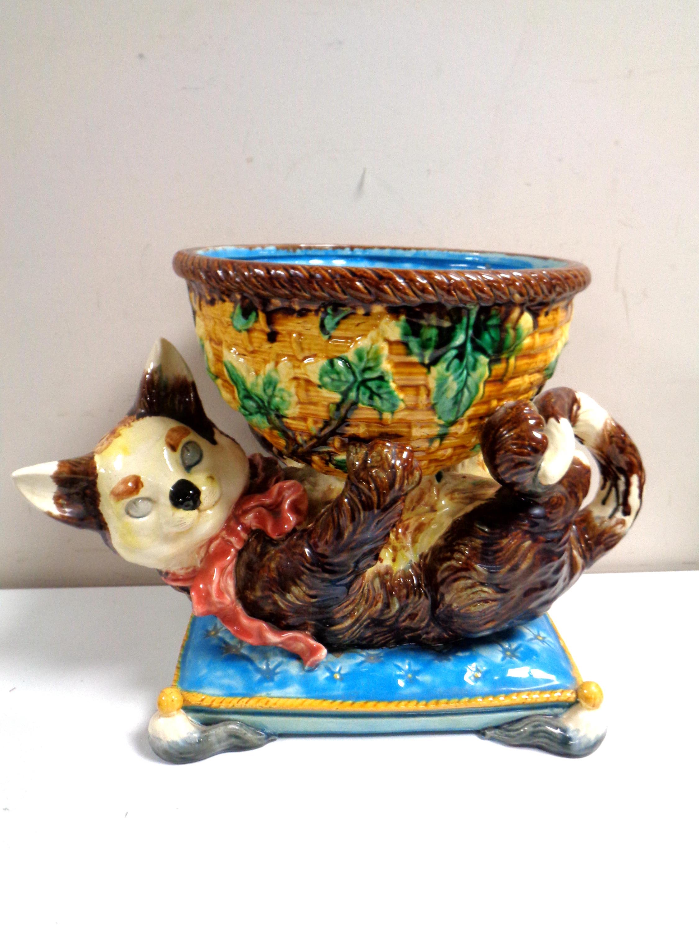 A Minton majolica jardiniere in the form of a cat playing with a wicker basket on cushion,