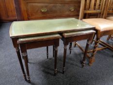 A nest of three tables with tooled green leather inserts