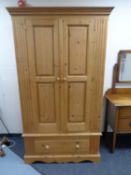 A stripped pine double door wardrobe fitted drawer beneath