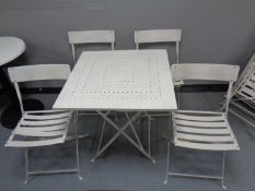A folding metal square cafe table and four chairs