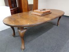 A 19th century oval oak wind out dining table with two leaves and winding handle