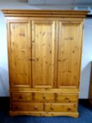 A pine Erinwood triple door wardrobe fitted five drawers