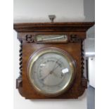 An Edwardian aneroid barometer with silver dial mounted on an oak board with barley twist column