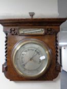An Edwardian aneroid barometer with silver dial mounted on an oak board with barley twist column