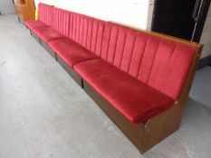 A four section function room bench seat upholstered in a maroon fabric,