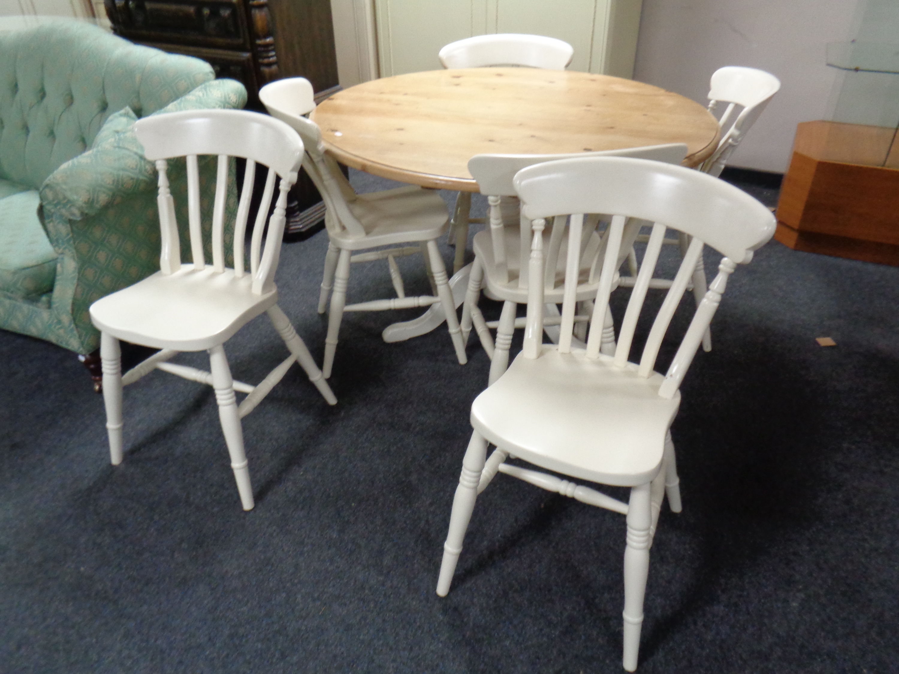 A circular pine dining table together with a set of six painted kitchen chairs