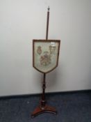 A Victorian mahogany pole screen with embroidered armorial panel