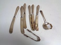 A set of six silver handed butter knives together with a silver spoon and a set of white metal