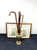 A brass embossed vase containing four assorted walking sticks,