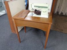 A 20th century Singer electric sewing machine in teak table